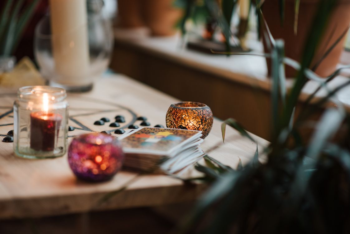 Cartas del tarot iluminadas por velas sobre un escritorio de madera, creando un ambiente místico para una consulta espiritual